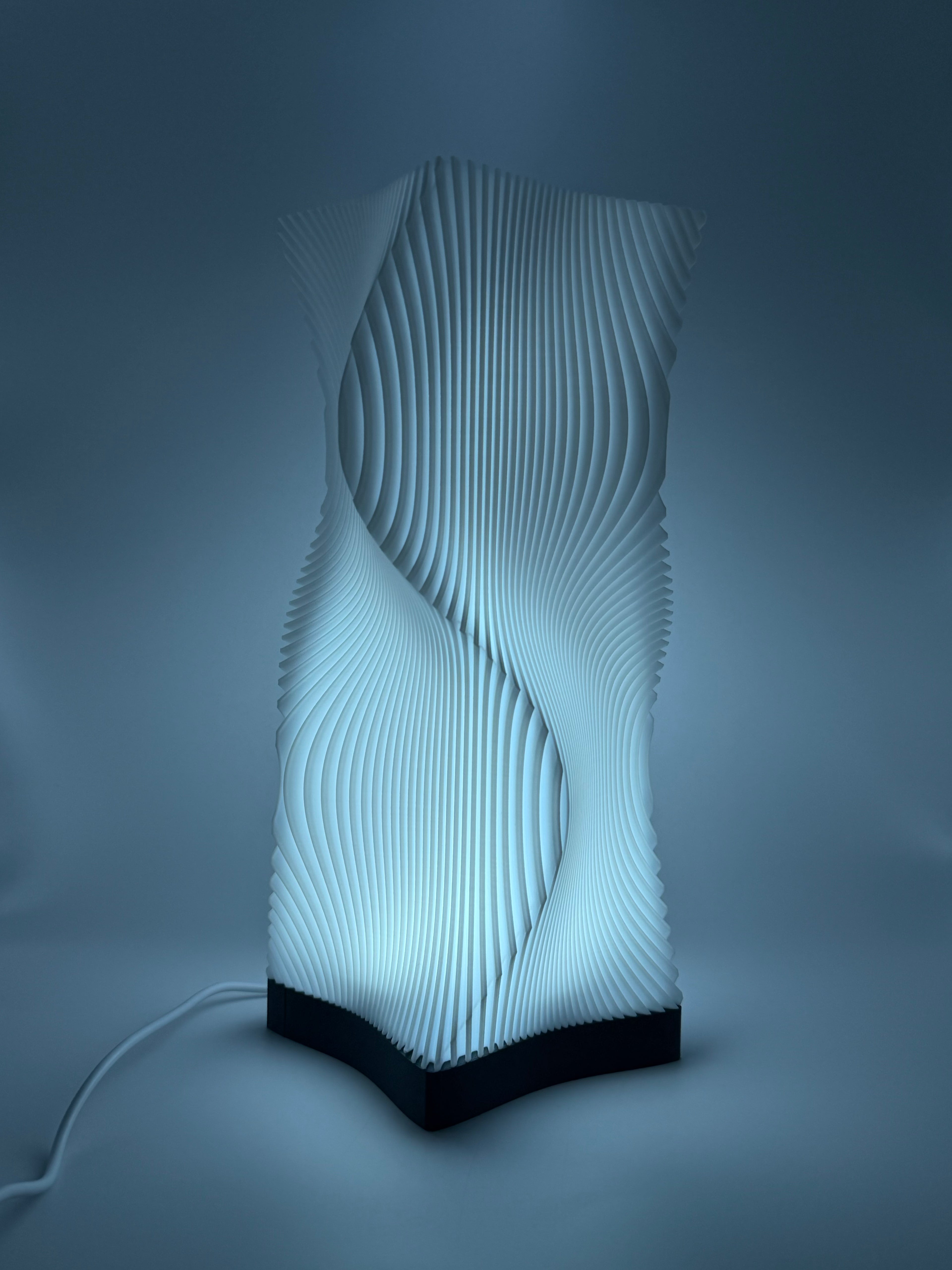 Moderne weiße Lampe mit 3D-gedruckter, wellenförmiger Lamellenstruktur, die ein indirektes Licht  wirft.