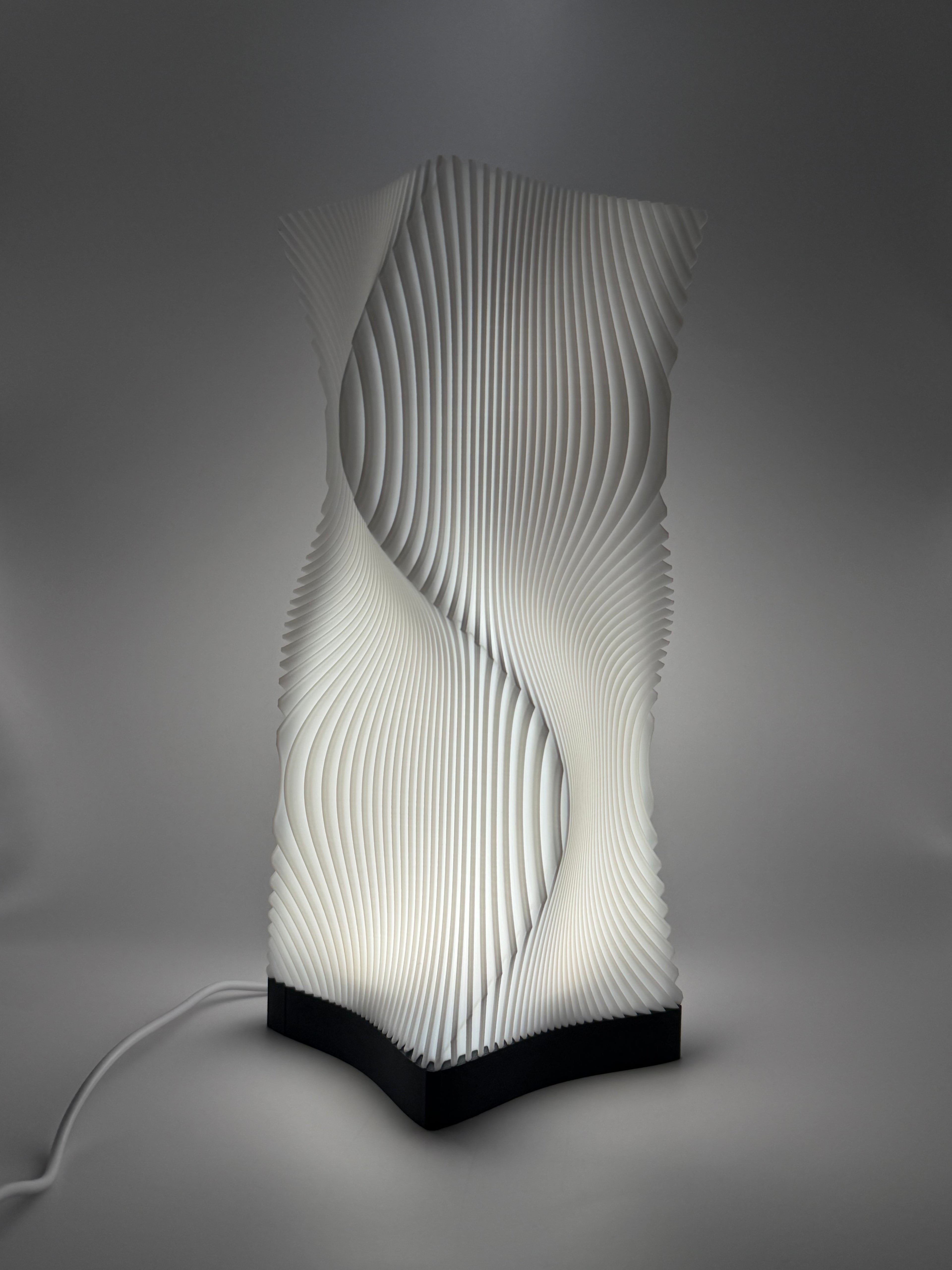 Moderne weiße Lampe mit 3D-gedruckter, wellenförmiger Lamellenstruktur, die ein indirektes Licht  wirft.