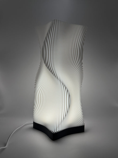 Moderne weiße Lampe mit 3D-gedruckter, wellenförmiger Lamellenstruktur, die ein indirektes Licht  wirft.